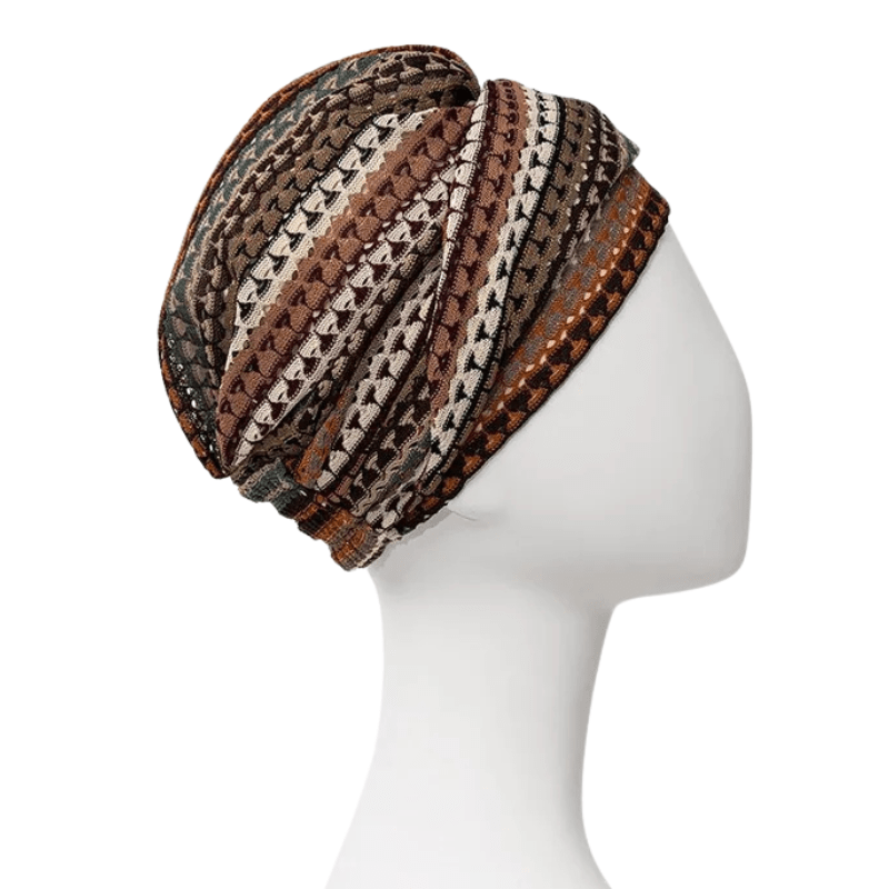Boho turban with open knit and patterned stripes in warm colors like brown, gold, and green, seen diagonally from front on mannequin