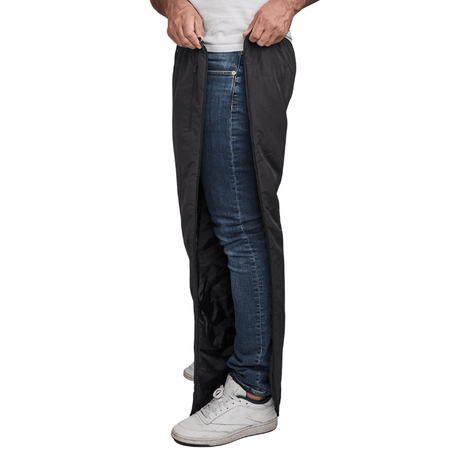 Man unzips black Dobsom thermal trousers on the side, over blue jeans and white sneakers