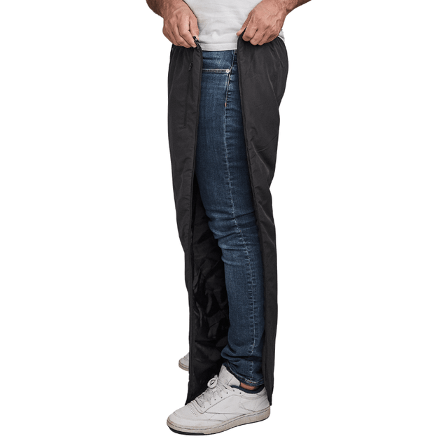 Mand lyner sorte Dobsom termobukser op i siden, over blå jeans og hvide sneakers